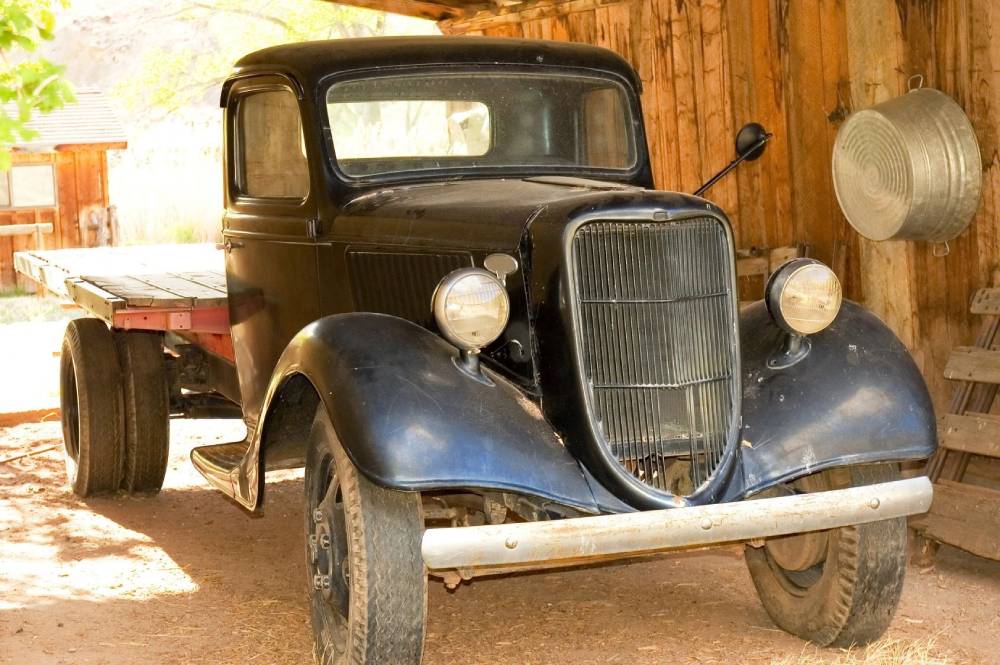 A black car parked in front of a wooden building.